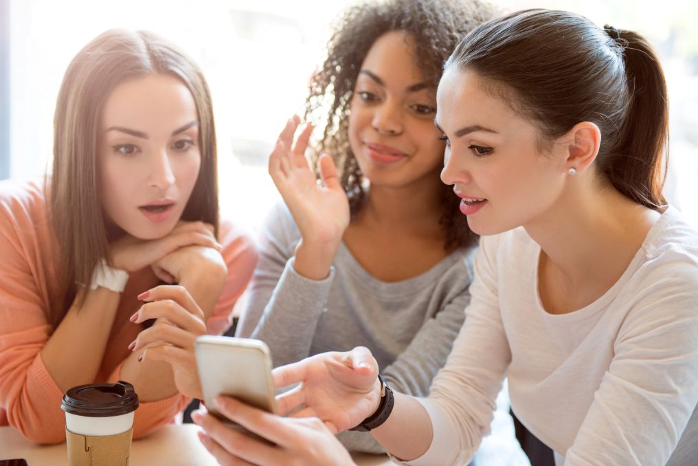 Girls looking at a phone together, gossiping