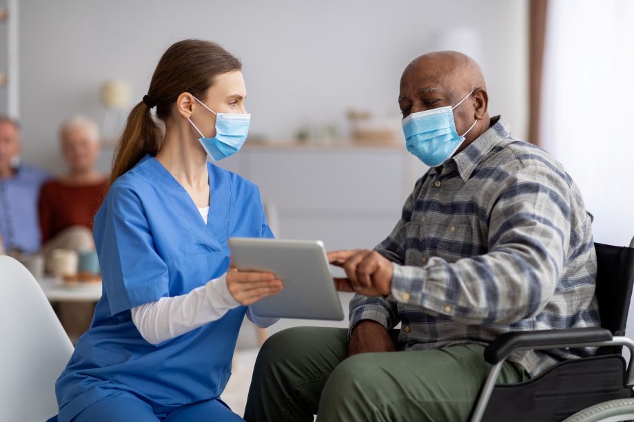 doctor showing male patient in wheelchair something on a tablet